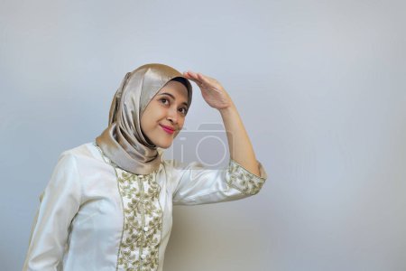 Mujer musulmana joven con entusiasmo mirando hacia arriba y mirando a la distancia. Curioso acerca de algo concepto