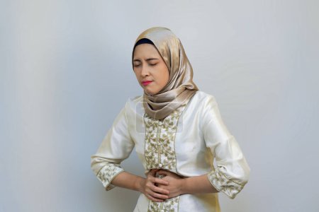 Muslimische Frau drückt Hunger und Schmerzen während des Ramadan-Fastens auf weißem Hintergrund aus