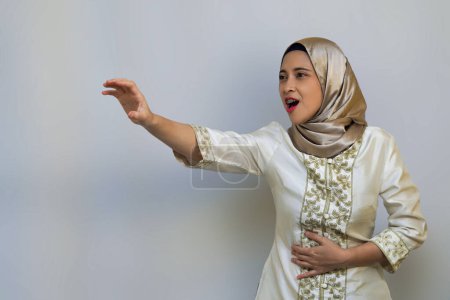Mujer musulmana expresando hambre y dolor durante el ayuno del Ramadán sobre fondo blanco