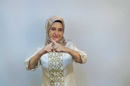 Mujer hijabi indonesia haciendo gestos prohibición con la mano o formando forma de X