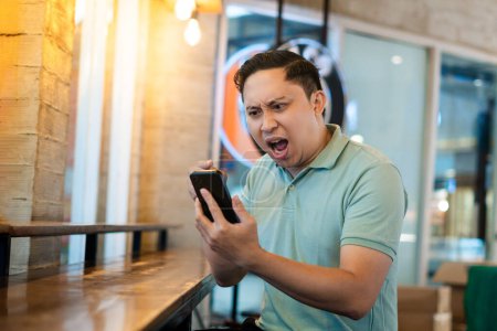 Homme adulte en colère et choqué par quelque chose sur son téléphone