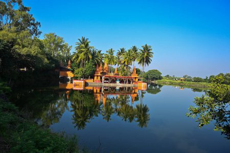 Photo for Temple on the lake. Hindu Temple. Palm trees and lake. Blue Sky.Water reflection. Maharashta. india - Royalty Free Image