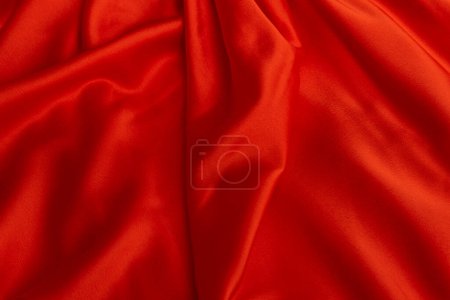 Textur aus rotem Satinstoff in Nahaufnahme. Seide oder Satin. Textiler Hintergrund. Einfaches helles Tuch.