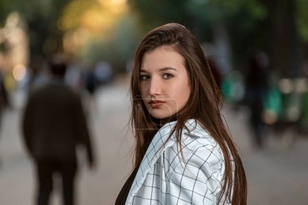 Photo for Gaze mischievous of raven-haired young woman . Portrait of attractive girl with long hair on park background - Royalty Free Image