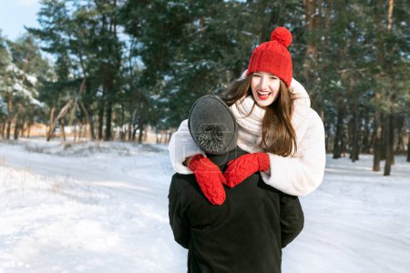 Téléchargez les photos : Rire belle fille sur l'épaule du gars. Couple amoureux amusez-vous pendant les vacances d'hiver dans la forêt enneigée. - en image libre de droit