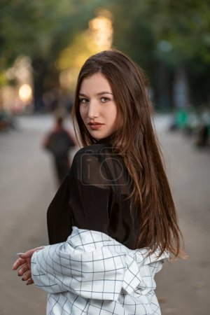 Photo for Portrait of an attractive young woman with long hair on park background. Gaze of raven-haired - Royalty Free Image