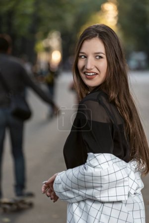 Photo for Portrait of smiling attractive young woman with long hair on park background. Gaze mischievous of raven-haired girl . - Royalty Free Image
