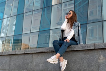 Photo for Attractive young woman in sunglesses in youth clothing on the city street. Stylish woman resting on city street - Royalty Free Image