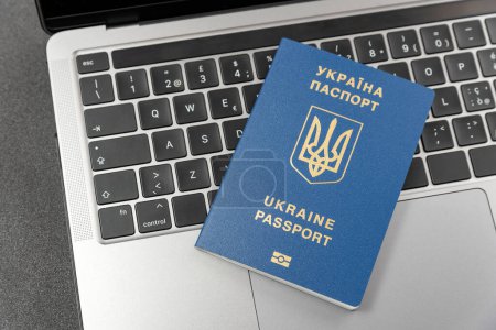Foto de Pasaporte ucraniano en teclado portátil. Vista superior. Registro en línea para ucranianos. Visado en línea o inmigración para los ciudadanos de Ucrania. - Imagen libre de derechos