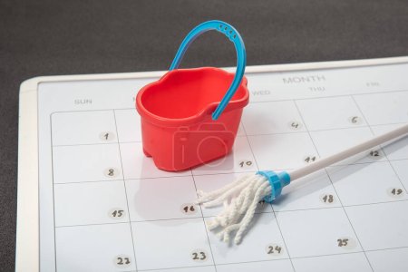 Small bucket and mop on the calendar. Concept of general cleaning. Planned cleanu