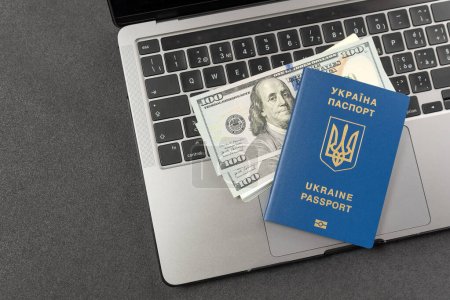 Téléchargez les photos : Enregistrement de documents en ligne en Ukraine. Passeport ukrainien, dollars et un ordinateur portable. Travail en ligne pour Ukrainiens. Paiements en espèces aux Ukrainiens. - en image libre de droit