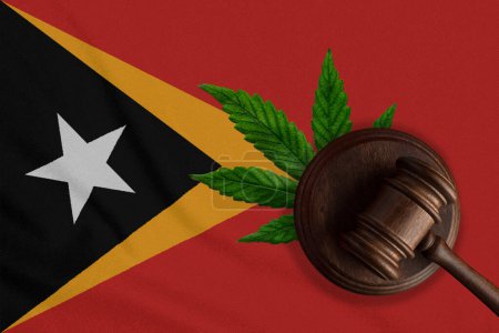 Téléchargez les photos : Drapeau du Timor oriental et marteau de justice avec feuille de cannabis. Croissance illégale de plantes de cannabis et propagation de drogues. - en image libre de droit