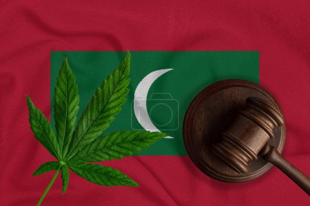 Téléchargez les photos : Goujon en bois judiciaire, feuille de chanvre frais et drapeau des Maldives. Vente et distribution illégales de marijuana. - en image libre de droit
