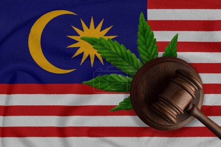 Téléchargez les photos : Gavel en bois du juge, feuille de chanvre frais et drapeau malaisien. Vente et distribution illégales de marijuana. - en image libre de droit