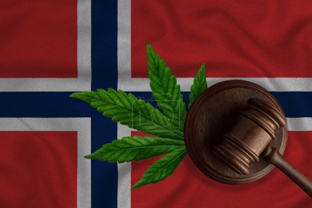Téléchargez les photos : Gavel et feuille de chanvre sur le fond du drapeau norvégien. Le concept de légalisation du cannabis en Norvège. - en image libre de droit