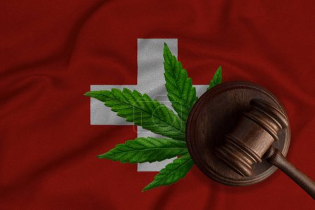 Téléchargez les photos : Gavel du juge et feuille de cannabis sur le fond du drapeau suisse. Le concept de légalisation de la marijuana en Suisse. - en image libre de droit