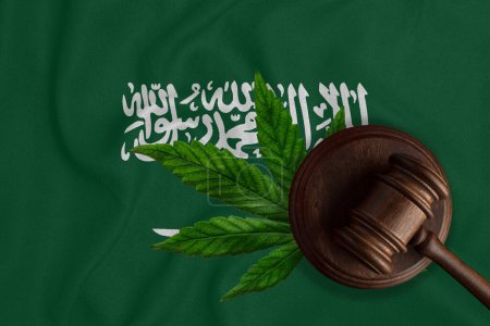 Téléchargez les photos : Un marteau sur le fond du drapeau de l'Arabie Saoudite. Le concept de légalisation de la marijuana en Arabie Saoudite. - en image libre de droit