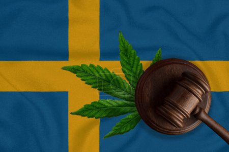 Téléchargez les photos : Un marteau sur le fond du drapeau de la Suède avec une feuille de marijuana. Le concept de légalisation du cannabis en Suède. - en image libre de droit