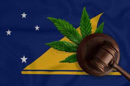 Téléchargez les photos : Un marteau sur le fond du drapeau de l'État de Tokelaujuana concept de légalisation. Drapeau Tokelau et cannabis. - en image libre de droit