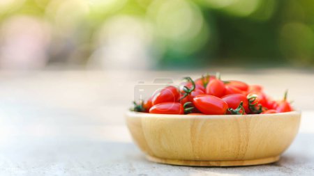 Foto de Los tomates rojos cereza frescos en un tazón de madera para comer frescos tienen un sabor suave. - Imagen libre de derechos