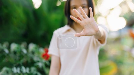 Photo for The woman raised her hand in refusal on nature background. - Royalty Free Image