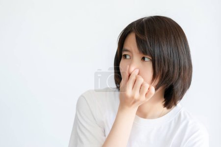 Photo for Asian woman with short hair covers her nose with her hand because something smells bad. - Royalty Free Image
