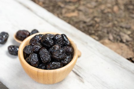 Ajwah dates in a wooden bowl on a white wooden background are fruits used to break the fast for Muslims.