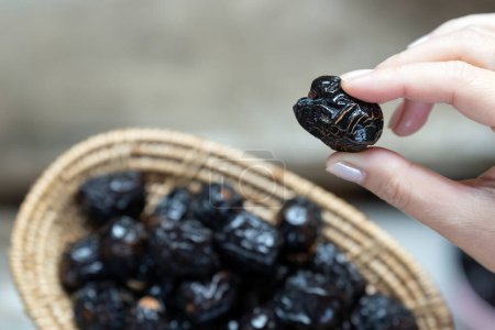 Close-up of woman's hand holding dried Ajwah dates that Muslims eat to break their fast in Ramadan.