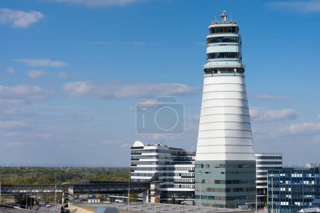 Téléchargez les photos : Aéroport de Vienne avec tour haute de contrôle du trafic aérien et divers bâtiments logistiques en face du ciel bleu - en image libre de droit