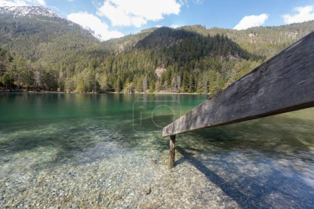 Téléchargez les photos : Paysage du lac idyllique Fernsteinsee au Tyrol Autriche avec rampe en bois menant à l'eau bleue verte boisée partiellement encore enneigée montagnes collines ciel clair nuages nature intacte - en image libre de droit