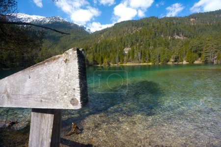 Téléchargez les photos : Paysage du Tyrol paysage paysage intact à idyllique lac de montagne clair avec clôture en bois ciel bleu partiellement nuageux neige couvert des pics et des forêts comme concept pour la détente dans la nature - en image libre de droit