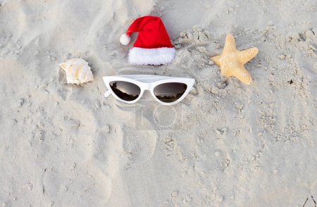 Photo for Christmas background Santa Claus hat on the beach with sunglases.Christmas card and advent calendar concept. Travel ticket sale concept for christmas holidays.Copy space.Top view.High quality photo - Royalty Free Image