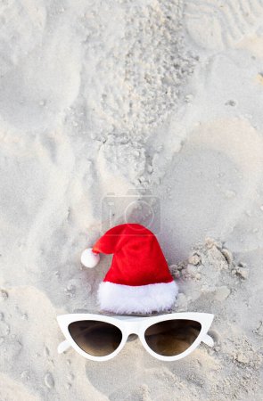 Photo for Christmas background Santa Claus hat on the beach with sunglases.Christmas card and advent calendar concept. Travel ticket sale concept for christmas holidays.Copy space.Top view.High quality photo - Royalty Free Image