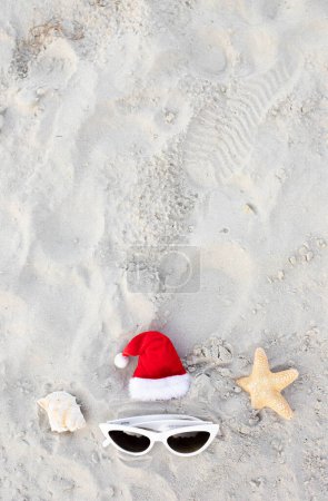 Photo for Christmas background Santa Claus hat on the beach with sunglases.Christmas card and advent calendar concept. Travel ticket sale concept for christmas holidays.Copy space.Top view.Vertical photo.High - Royalty Free Image