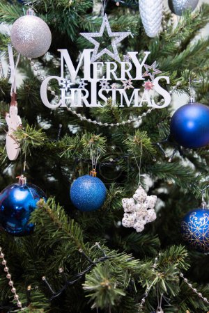 Foto de Tarjeta de Navidad con inscripción Feliz Navidad en el árbol de Navidad con juguetes.Espacio de copia.Cerrar .Foto vertical. Foto de alta calidad - Imagen libre de derechos