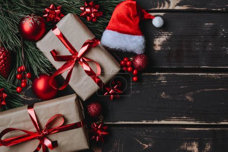 Foto de Vista superior foto Navidad flatlay cajas de regalo, juguetes de árbol de Navidad rojo, Santa sombrero y abeto brance sobre fondo de madera. Fondo de Navidad con espacio para text.Copyspace. - Imagen libre de derechos