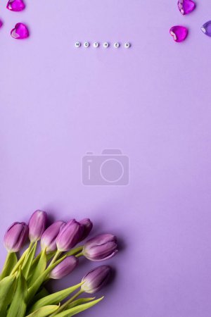 Foto de Spring tulip and text mother on english laid out of multi-colored cube on violet background.Copy space.Top view photo.Vertical photo. - Imagen libre de derechos