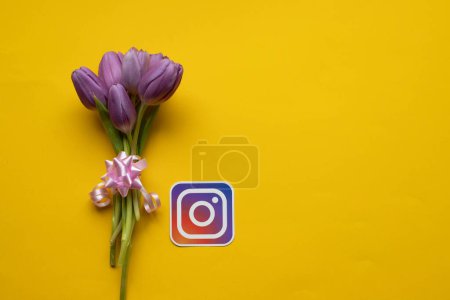 Foto de Icono de Instagram y tulipanes frescos de primavera sobre fondo amarillo.Copiar el espacio.Vista superior de la foto. - Imagen libre de derechos