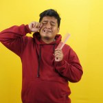 asian man holding his fingers with his hand. studio shot on yellow background