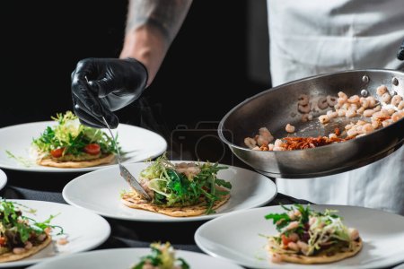 Téléchargez les photos : Le chef au restaurant faisant Tacos de crevettes épicées avec salade et salsa
. - en image libre de droit