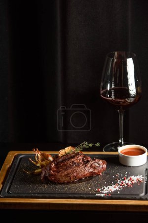 Succulent grillowany stek wołowy z czerwonym winem, przyprawy, świeże rozmaryn i grillowane warzywa na desce do krojenia.