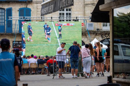 Téléchargez les photos : A Perigueux, Dordogne, France 03 Juin 2023 : United in Sports : Spectators Watching a Rugby Match Broadcast in a Public Square - en image libre de droit