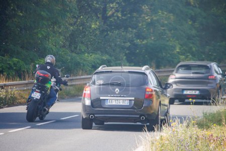 Téléchargez les photos : Dordogne, France 23 juillet 2023 : Un motocycliste dépasse une voiture, la sécurité routière est soulignée - en image libre de droit