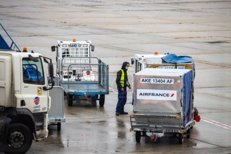 Téléchargez les photos : Aeroport Charles de Gaulle, France 24 octobre 2023 : Le personnel de l'aéroport charge les bagages dans les avions avec des véhicules Charlatte - en image libre de droit