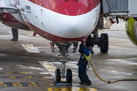 Téléchargez les photos : Aeroport Charles de Gaulle, France 24 octobre 2023 : Un travailleur harmonise un tuyau de carburant avec le port de ravitaillement d'un aéronef - en image libre de droit