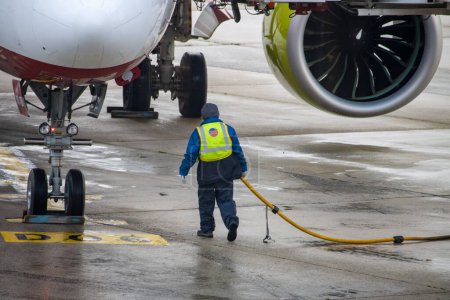 Téléchargez les photos : Aeroport Charles de Gaulle, France 24 octobre 2023 : Un travailleur déplace un tuyau de carburant d'un aéronef sur l'aire de trafic - en image libre de droit