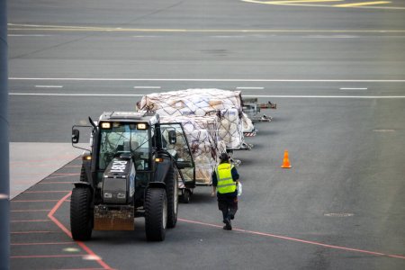 Téléchargez les photos : Aéroport Helsinki-Vantaa, Finlande, 24 octobre 2023 : Tracteur avec remorque sur le tarmac de l'aéroport - en image libre de droit