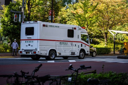 Téléchargez les photos : Tokyo, Japon, 26 octobre 2023 : Ambulance en mouvement sur une rue bordée d'arbres - en image libre de droit