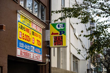 Photo for Tokyo, Japan, 27 October 2023: Parking Sign with Rates on Urban Building - Royalty Free Image