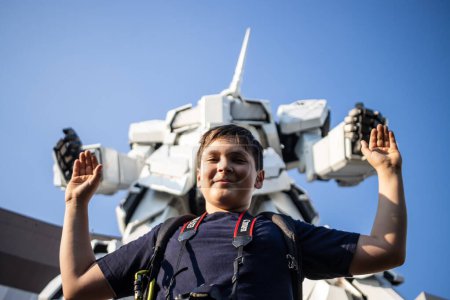 Photo for Tokyo, Japan, 27 October 2023 : Child posing with the Gundam robot statue in Odaiba - Royalty Free Image
